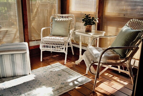 Une pièce baignée de lumière, avec des chaises en osier, une petite table et une plante en pot.