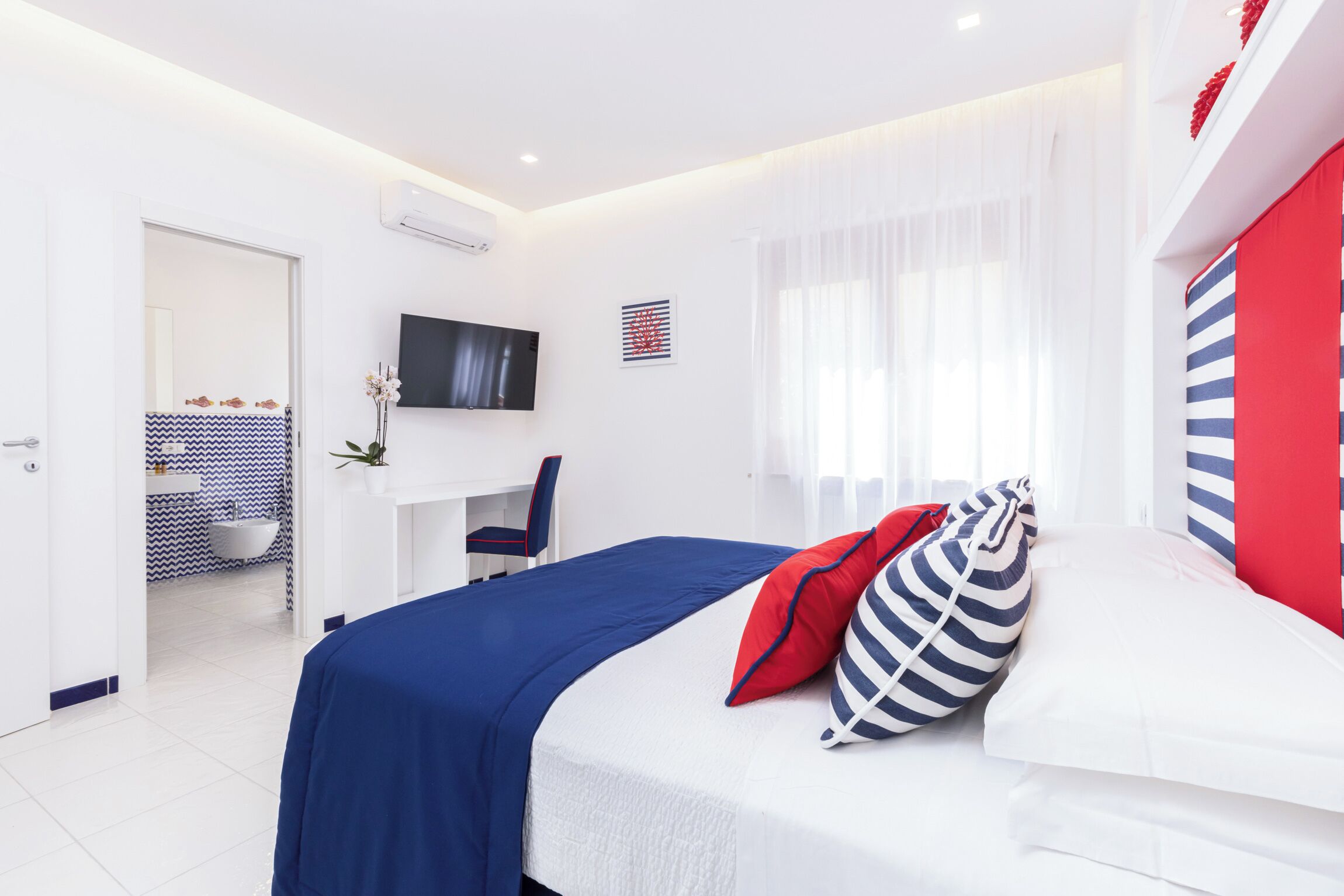 Una habitación de hotel moderna con cama, escritorio y televisor.
