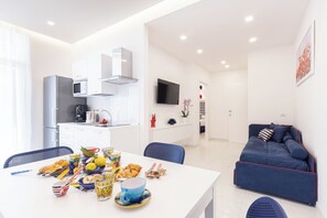 Un espace de vie moderne comprenant un coin repas, une cuisine et un canapé bleu.