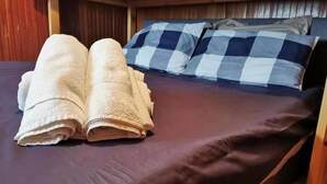 A neatly made bed with a dark mattress and two rolled-up towels on the left side. - Newly Renovated Apartment in Cervinia's Heart (Valtournenche)