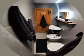 A compact bathroom with a wooden door, two sinks, a mirror, and a towel rack. - Newly Renovated Apartment in Cervinia's Heart (Valtournenche)
