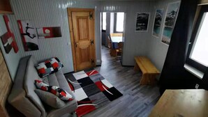 A compact living space with a sofa, a wooden bench, a patterned rug, and a door leading to another room. - Newly Renovated Apartment in Cervinia's Heart (Valtournenche)