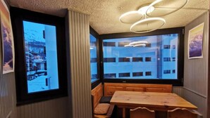A cozy room with a large window, a wooden table, and a bench. - Newly Renovated Apartment in Cervinia's Heart (Valtournenche)