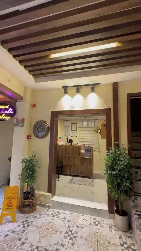 A reception area with a wooden reception desk, potted plants, and a tiled floor.