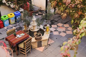 A small outdoor seating area with a table and chairs, surrounded by potted plants and a decorative fountain. - Sirvani Konagi (Gaziantep)