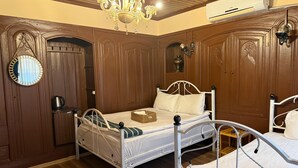 Una camera da letto con un letto in metallo bianco, pannelli in legno, un lampadario e un condizionatore d'aria.