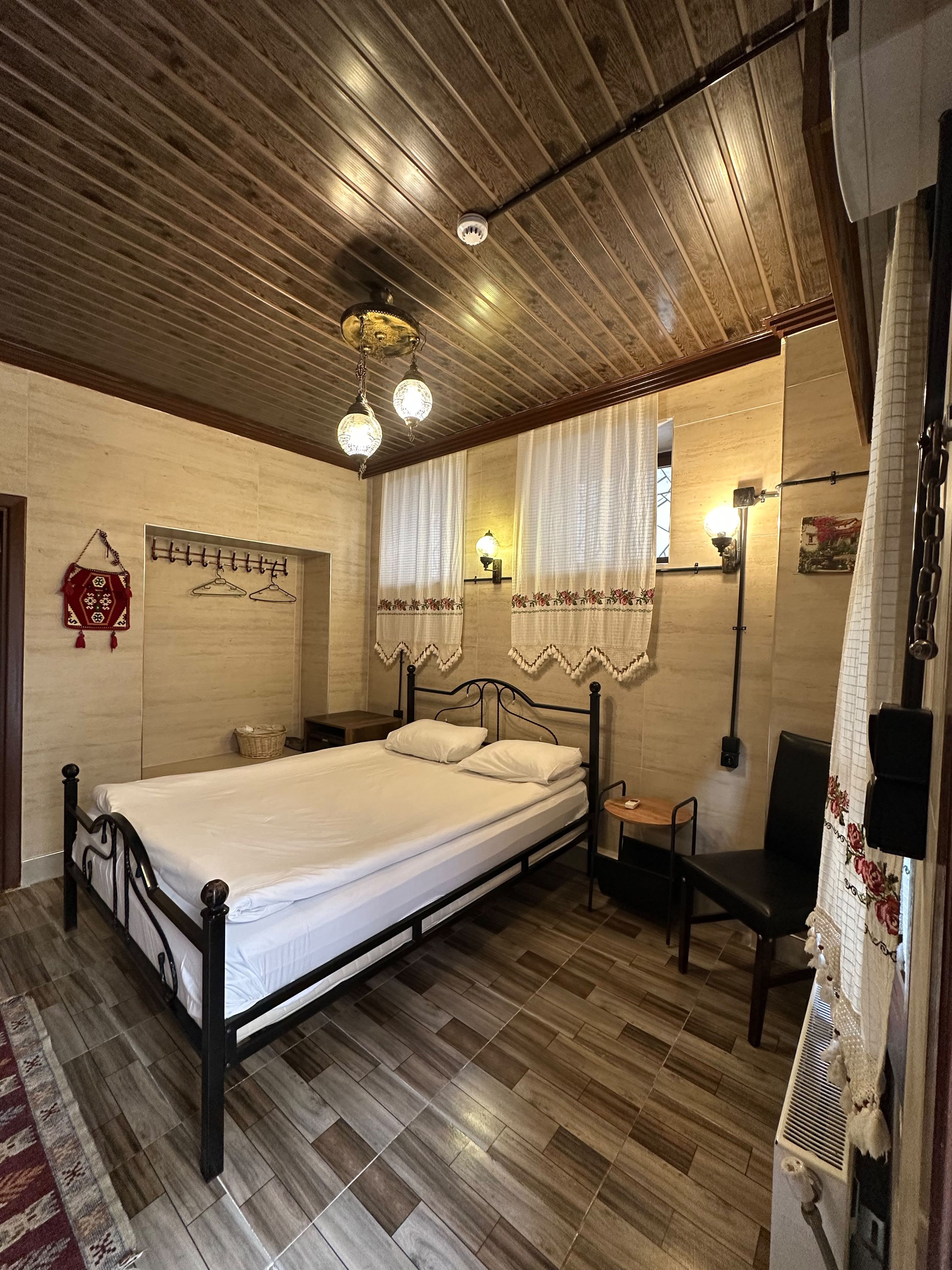 Una habitación con una cama, una silla, una lámpara de pared y un ventilador de techo.