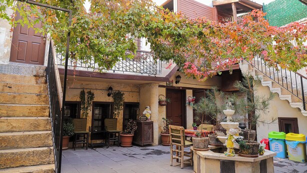 Un cortile con una scala in legno, piante in vaso e posti a sedere all'aperto.