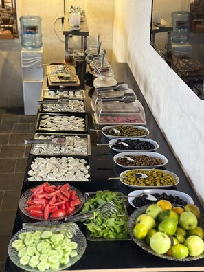 Un bufé con diversas opciones de comida, incluyendo frutas, verduras y carnes.