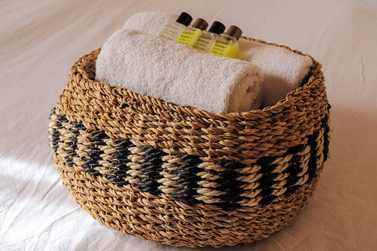 A woven basket with a towel and bottles of Sirvan Konagi body lotion.