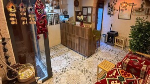 Un'accogliente area reception con scrivania in legno, uno specchio e un angolo salotto con tappeto decorato.