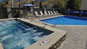 A hot tub and a swimming pool with lounge chairs, a wooden deck, and a view of mountains. - Great Condo just 3 min walk to Lionshead Gondola. (Vail)