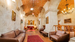 A spacious lobby with leather sofas, a red rug, and a wooden dining area.