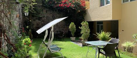 A patio with a table and chairs, surrounded by potted plants and a stone wall.
