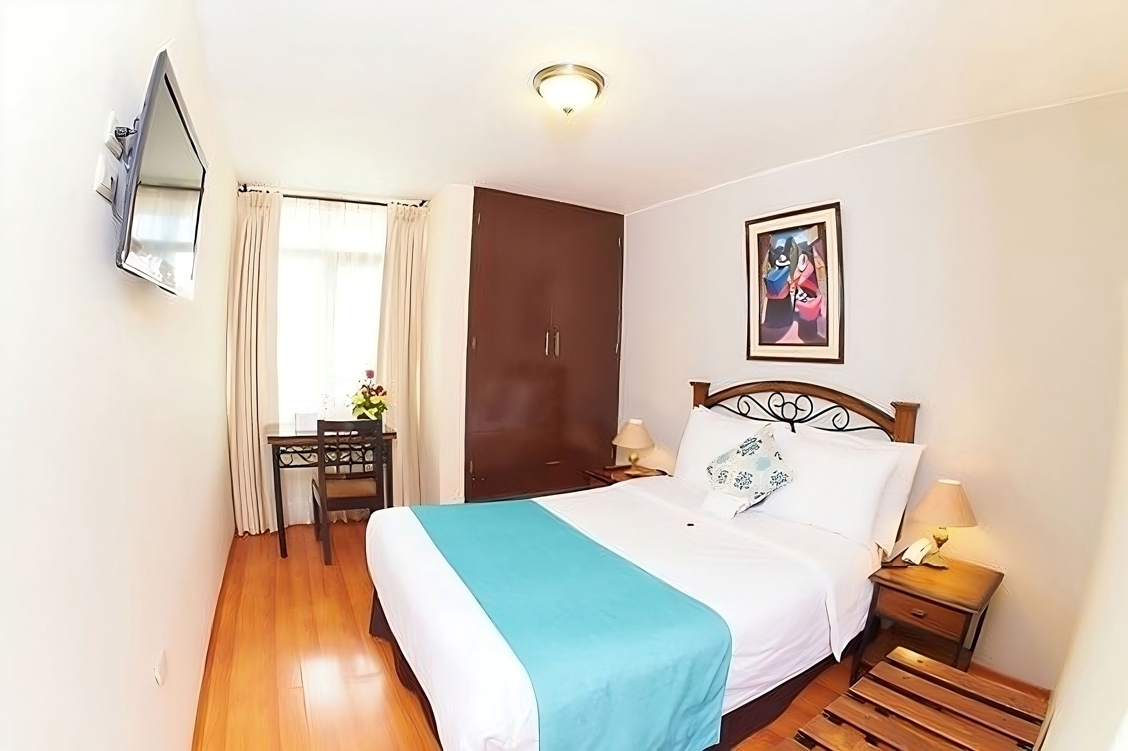 A bedroom with a bed, a desk, a wardrobe, and a painting on the wall.