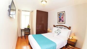 A bedroom with a bed, a desk, a wardrobe, and a painting on the wall.