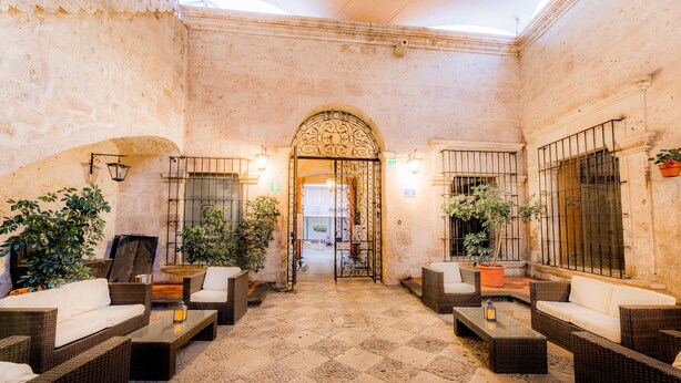 A courtyard with wicker furniture, potted plants, and a tiled floor.