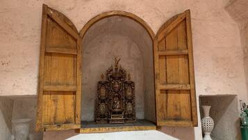 A chapel with an ornate altar, wooden arches, and a white wall.