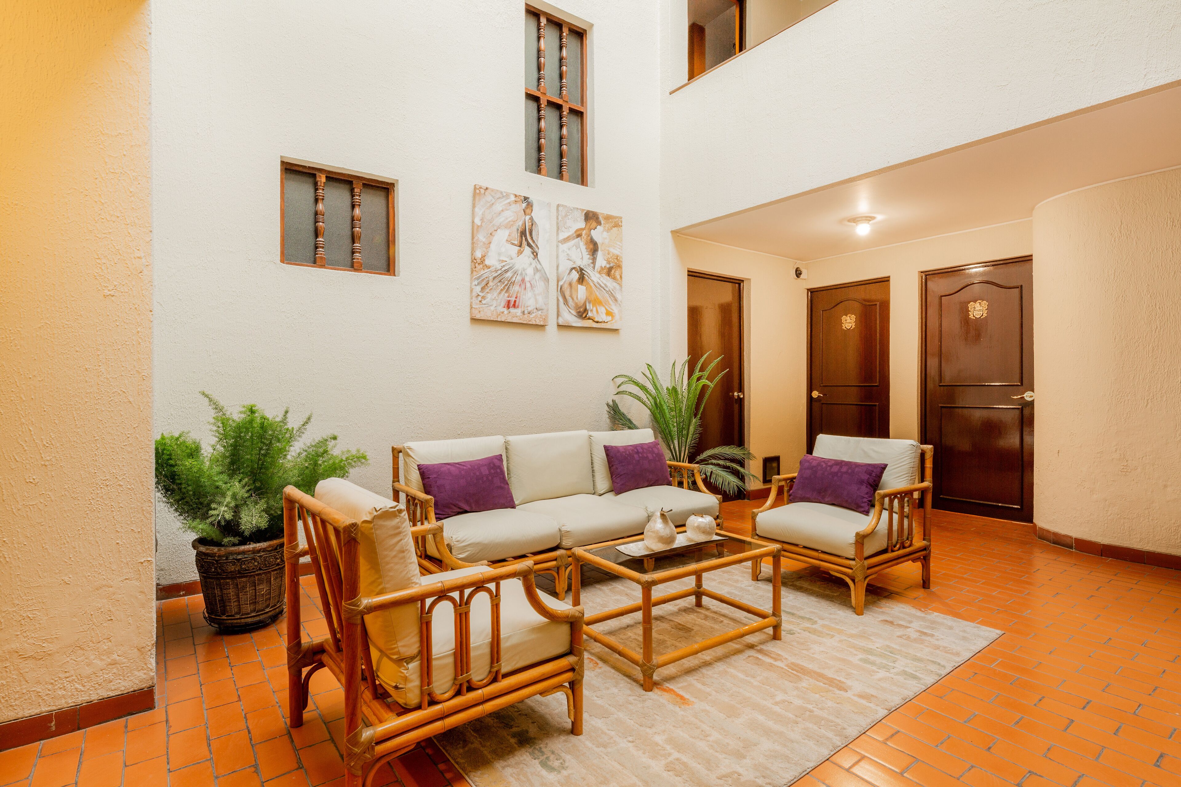 Amplia sala de estar con un conjunto de sofá, dos sillones, una mesa de centro y plantas en macetas.