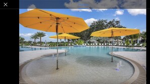 A pool area with yellow umbrellas and lounge chairs. - Cozy Condo on Golf Course/Summer Rental/ Fort Myers  (Fort Myers)