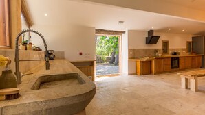 A modern kitchen with a stone sink, wooden cabinets, and a large window overlooking a garden. - eco-lodge with natural swimming pool (PUECHABON)