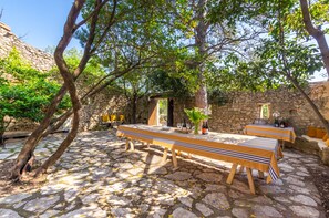 A stone courtyard with tables set up for dining, surrounded by trees and stone walls.