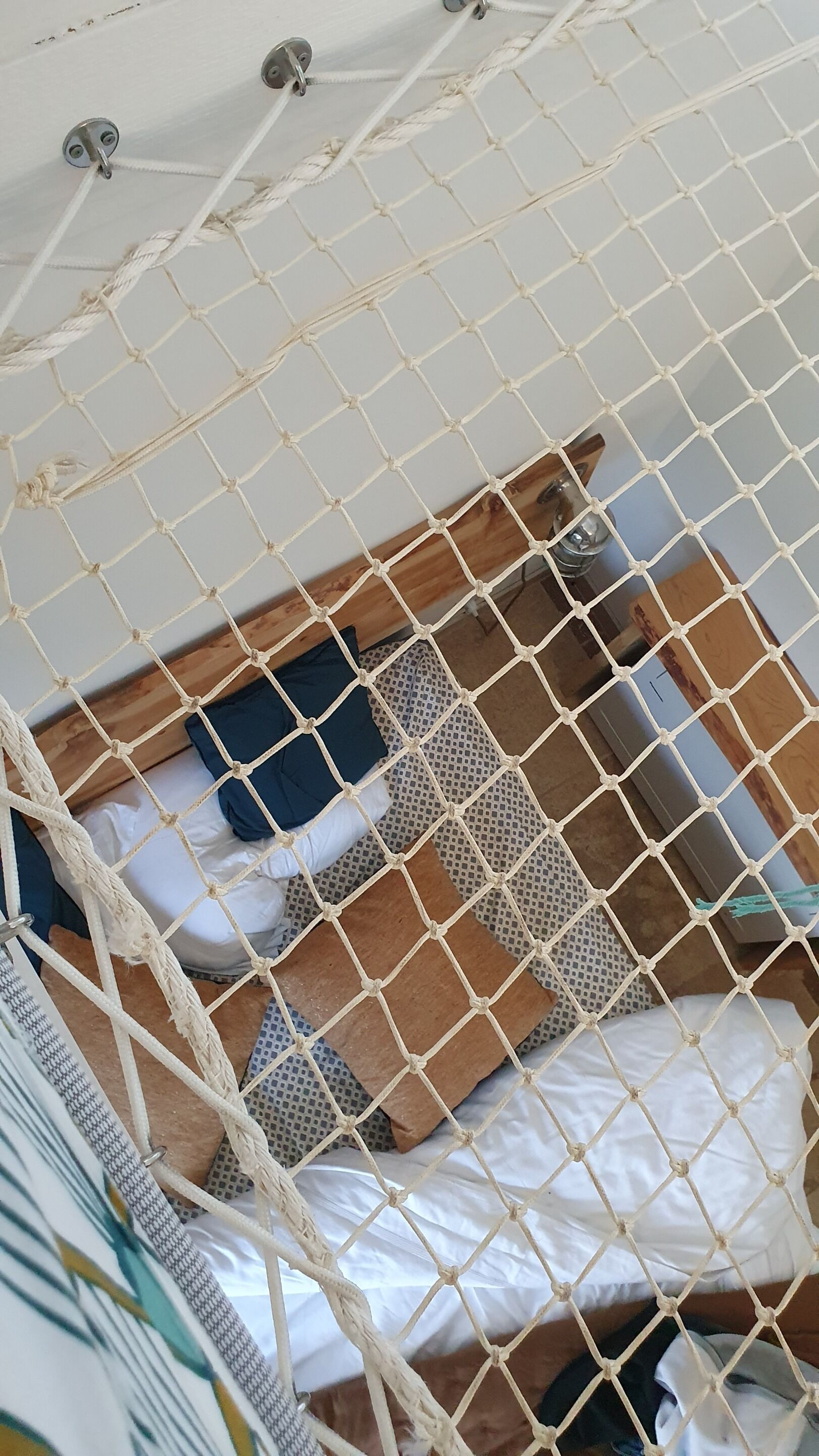 Een kamer met een bed, kussens en een houten hoofdeinde.