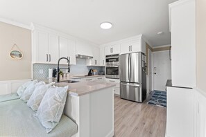 Una cocina moderna con armarios blancos, electrodomésticos de acero inoxidable y una isla central.