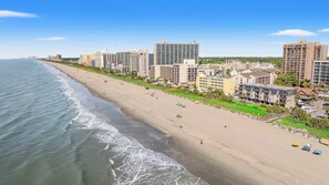 A coastal cityscape with a sandy beach, high-rise buildings, and a clear sky. - Long Bay Dunes E1 - Ocean Front 2 Bed/2 Bath Condo - Pool - 1st Floor Unit (Myrtle Beach)