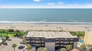 A beachfront hotel with a pool, beach umbrellas, and a view of the ocean. - Long Bay Dunes E1 - Ocean Front 2 Bed/2 Bath Condo - Pool - 1st Floor Unit (Myrtle Beach)