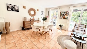 A dining area with a round table, chairs, a buffet cabinet, and a cactus decoration. - Villa 3 bed 2 bath 6 pers, south facing, Golfe St Tropez, air-conditioned, free wifi (Grimaud)