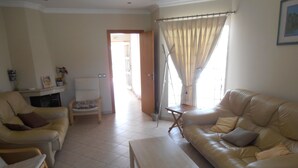 Una sala de estar con sofá, sillas, una mesita y una puerta que da a otra habitación.