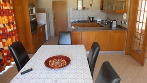 Cocina compacta con zona de comedor, que incluye microondas, estufa, fregadero y una mesa con sillas.