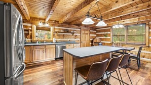 Une cuisine de style rustique, avec des éléments en bois, un grand îlot central, un réfrigérateur en acier inoxydable et des armoires en bois.