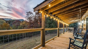 Une terrasse en bois avec une rambarde, des guirlandes lumineuses et des bancs.