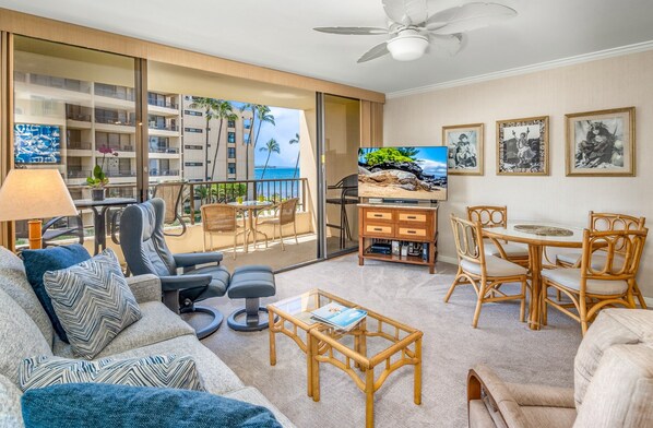 Une chambre d’hôtel avec un balcon, une télévision, un coin repas et des œuvres d’art aux murs.