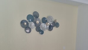 Une chambre à coucher avec un lit, une table de chevet avec une lampe, un élément de décoration murale et un plancher en bois.