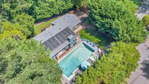 Vista aérea de una casa con piscina, rodeada de árboles frondosos.