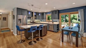 Una cocina moderna con armarios grises, electrodomésticos de acero inoxidable y taburetes de bar azules.