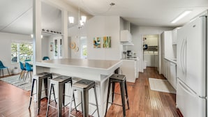 Een moderne keuken met witte kasten, een centraal eiland met krukken en uitzicht op de omgeving.