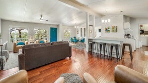 Een ruime woonkamer met een grote bank, een eettafel en een keuken met barstoelen.