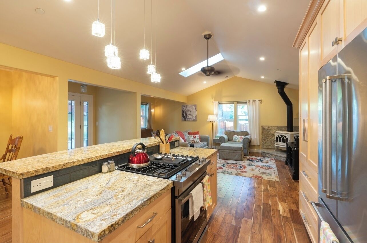 A spacious kitchen with granite countertops, a stainless steel refrigerator, and a large island with a kettle.