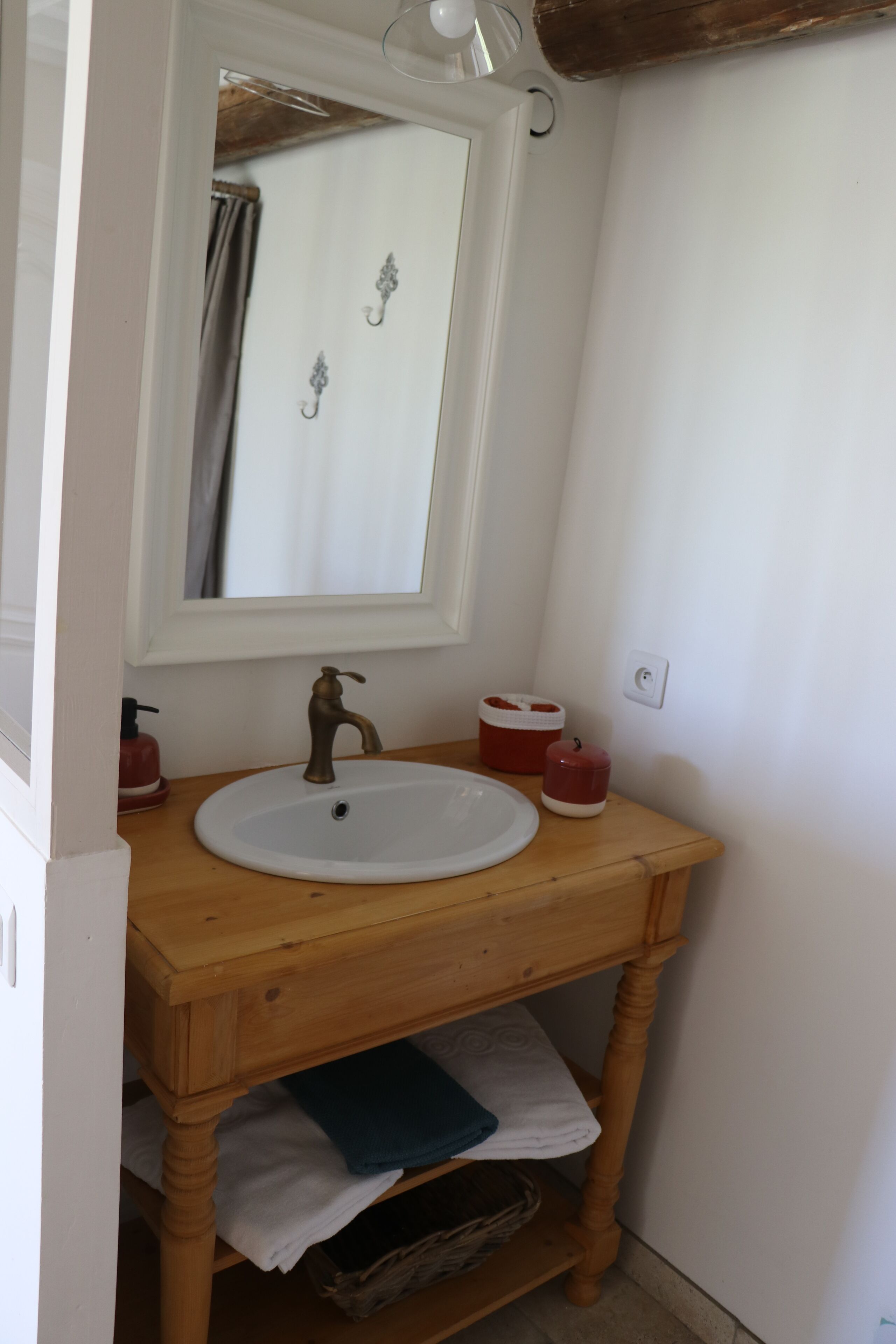A bathroom with a wooden vanity, a white sink, a mirror, and a towel rack.