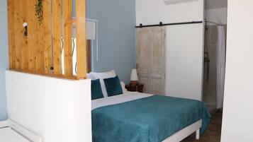 Une chambre comprenant un lit, une cloison en bois, une armoire et un espace douche.