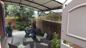 An outdoor patio with a table and chairs, wicker sofas, and potted plants. - Warm, air-conditioned, 2-bedroom house 3 km from La Ciotat beaches. (Ceyreste)