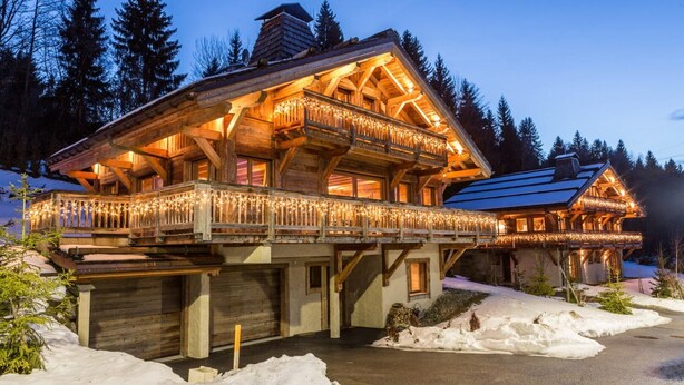 Una cabaña de madera con balcón y porche cubierto, rodeada de nieve.
