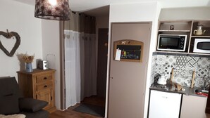 Un espacio habitable compacto con kitchenette, un comedor con mesa y sillas de madera, y una zona de estar acogedora con sofá.