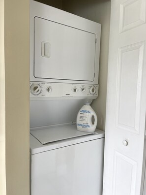 A front-loading washing machine with control knobs and a detergent bottle on the door.