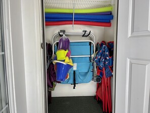 A storage area with shelves holding colorful mats and a blue folding chair.