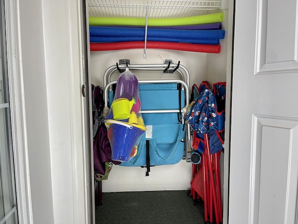 A storage area with shelves holding colorful mats and a blue folding chair.